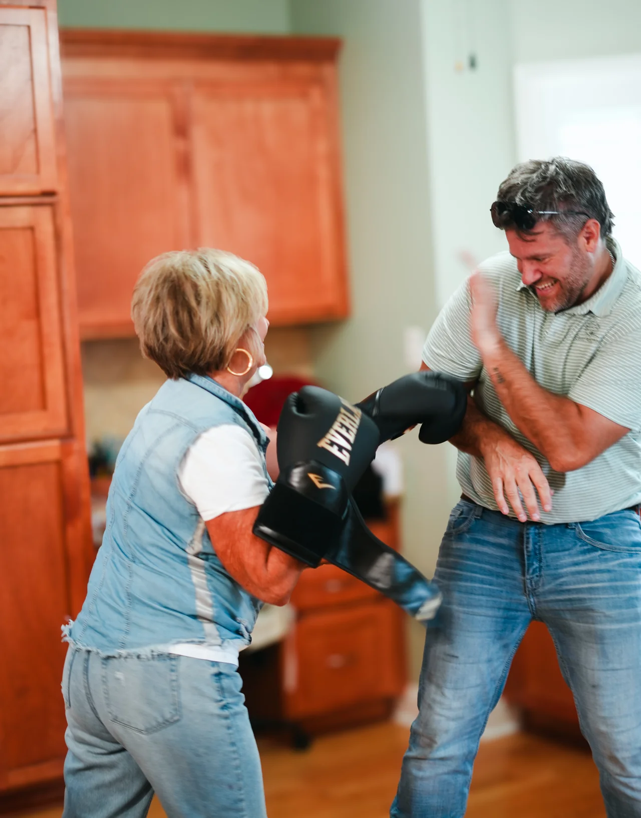 A woman wearing boxing gloves sharing a playful moment with a smiling man.
