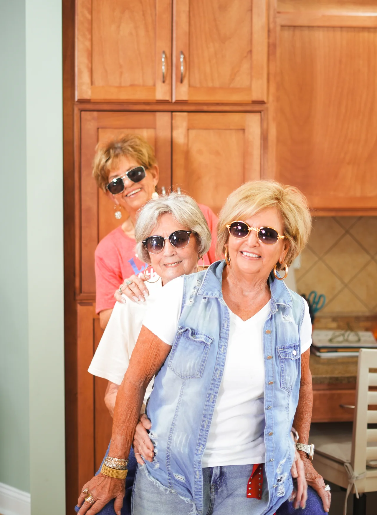 Three women wearing sunglasses and smiling together.