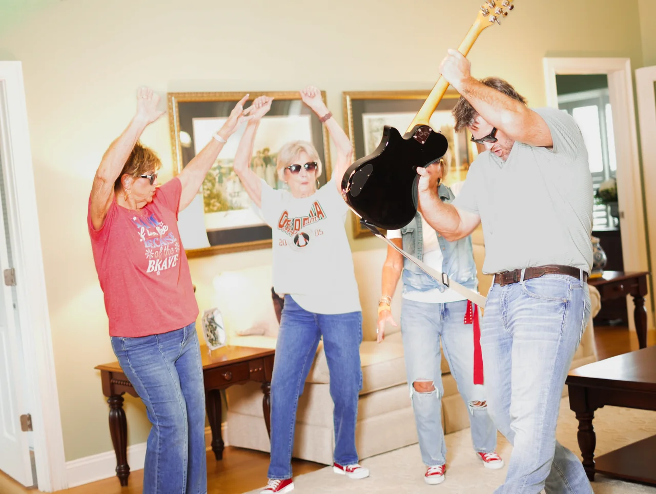 A man playing guitar while three women dance.