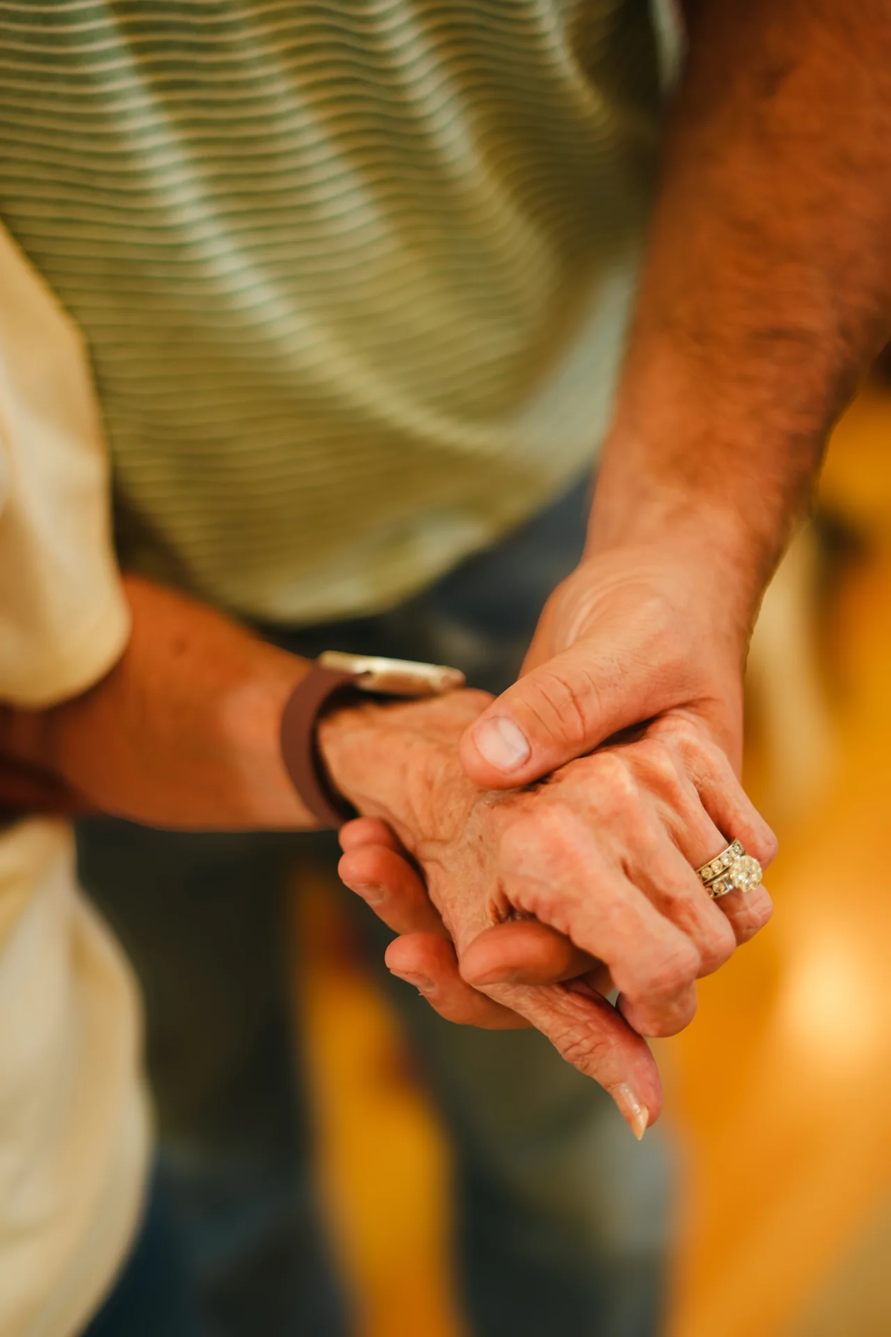 Close-up of one person gently holding another person’s hand.